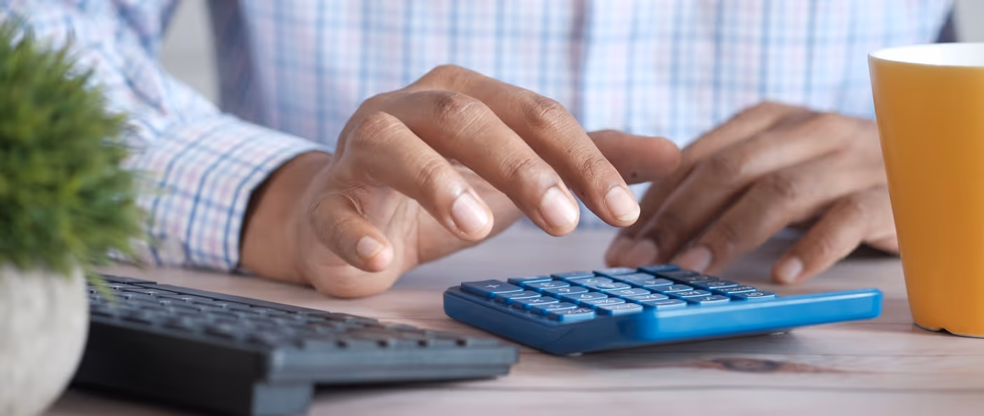 Hands using a calculator at a desk.