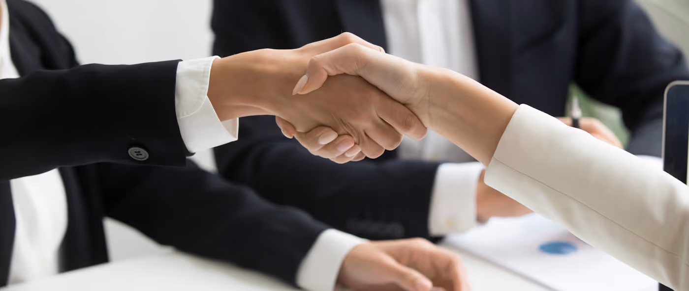 A handshake across a desk during a meeting.